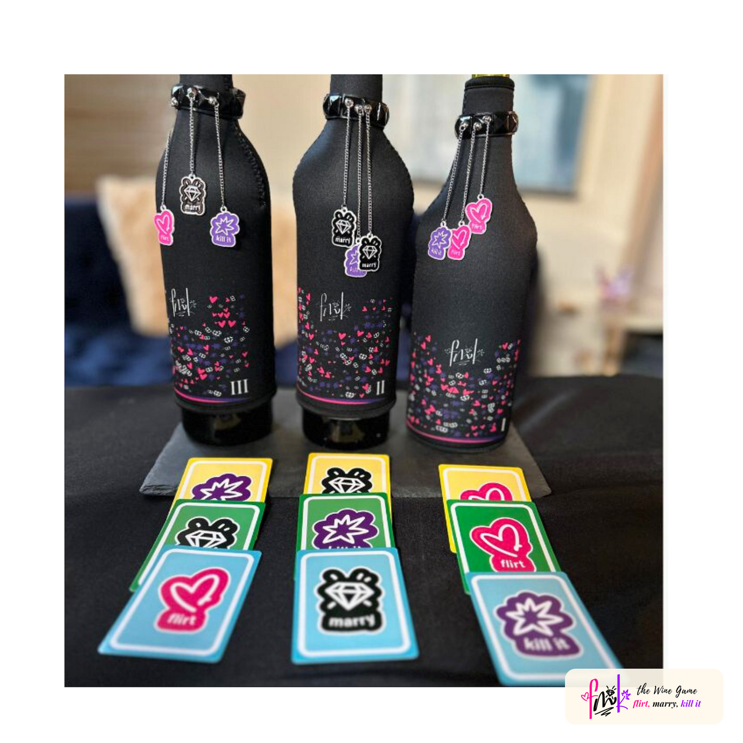 Three decorated wine bottles with black wraps and colorful heart patterns, accompanied by various game cards and charms on a table.