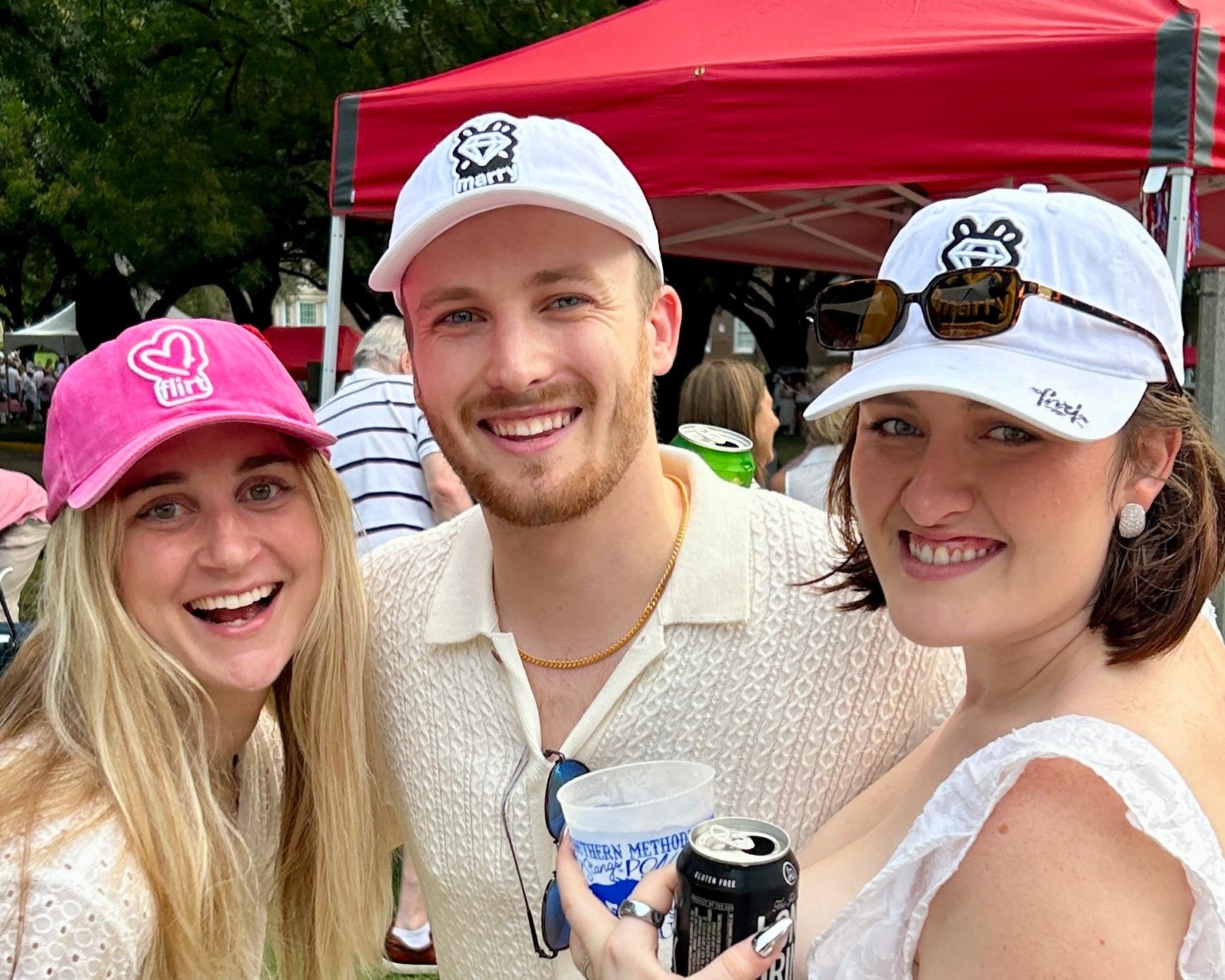 Three people posing together wearing FMK the wine game hats